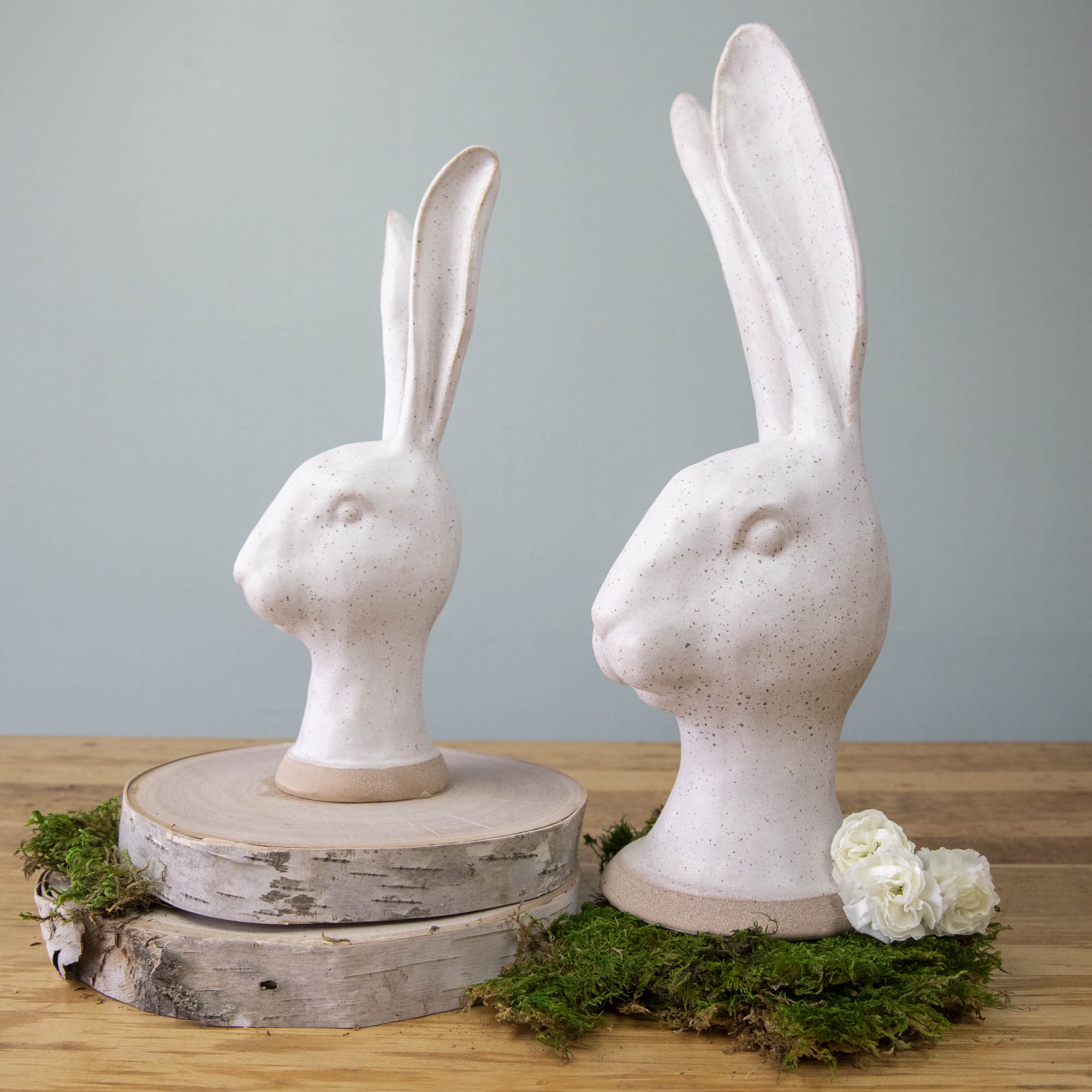 An enchanting HomArt Matte White Ceramic Hares heads on moss, serving as a charming garden decoration.