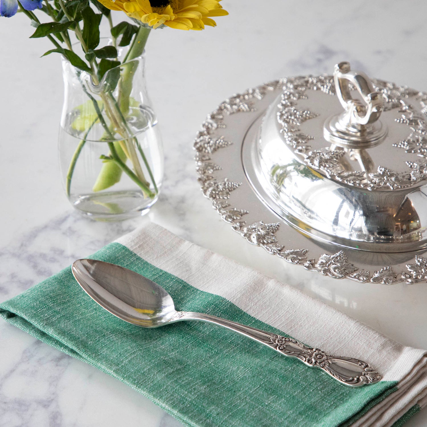 A Hester &amp; Cook vintage silver-plate serving spoon sits on top of a green napkin.