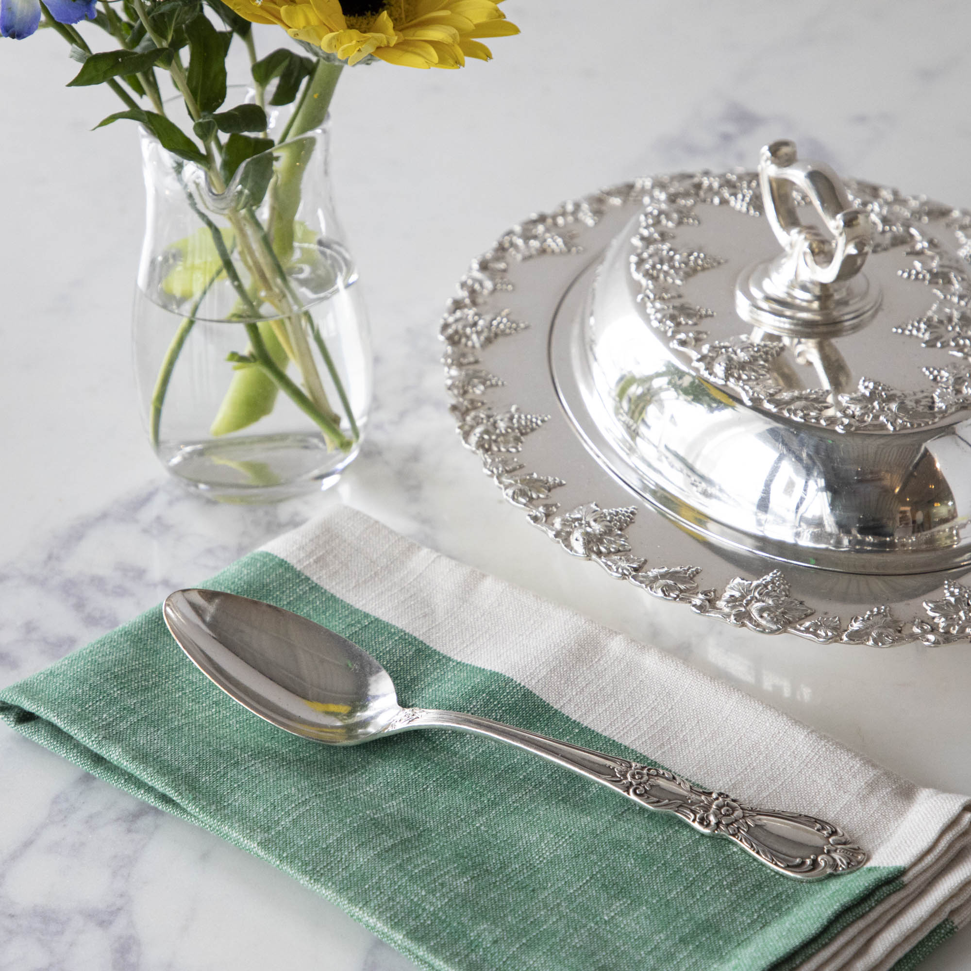 A Hester &amp; Cook vintage silver-plate serving spoon sits on top of a green napkin.
