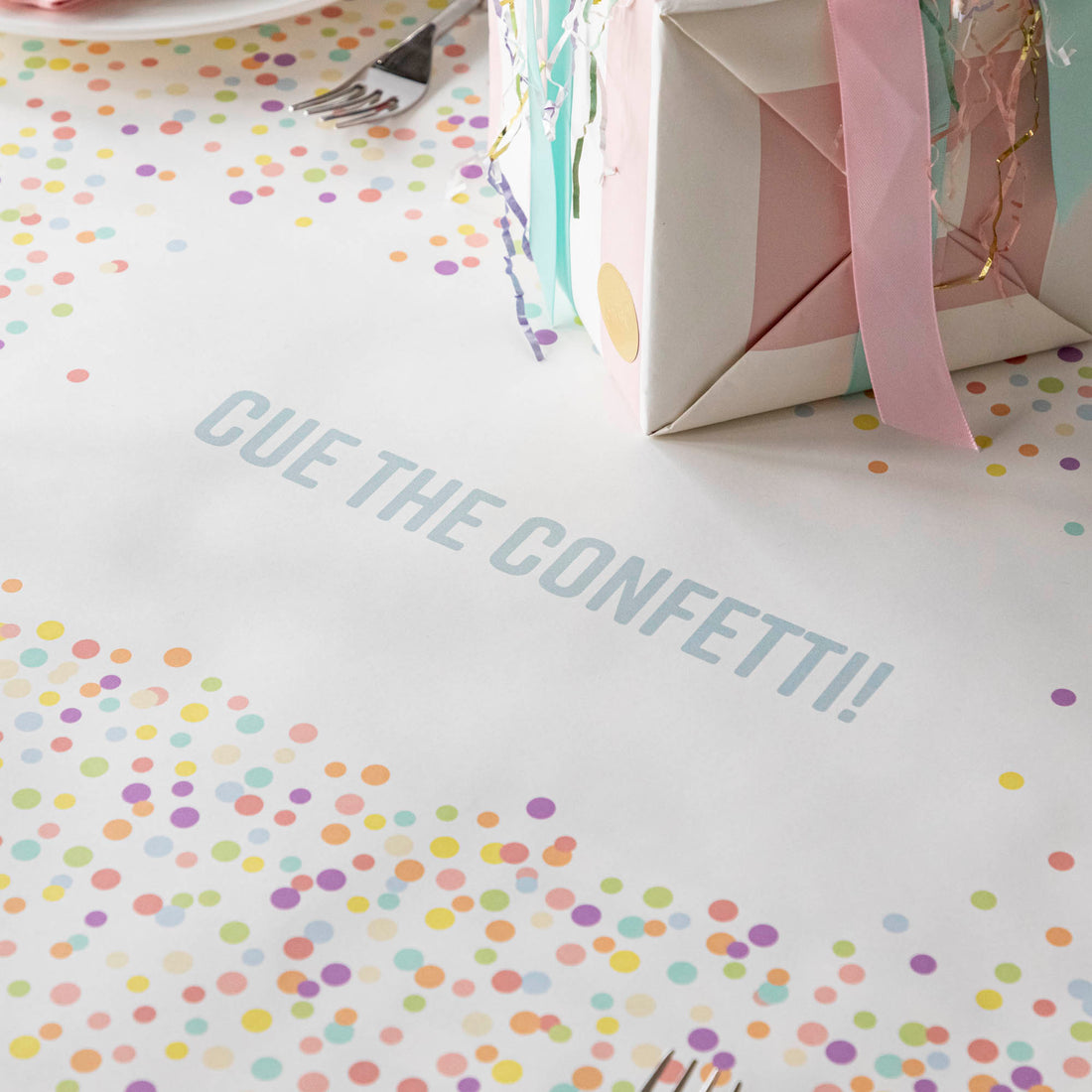 Close-up of the Confetti Sprinkles Personalized Runner under a birthday table setting, with &quot;CUE THE CONFETTI!&quot; printed in blue.