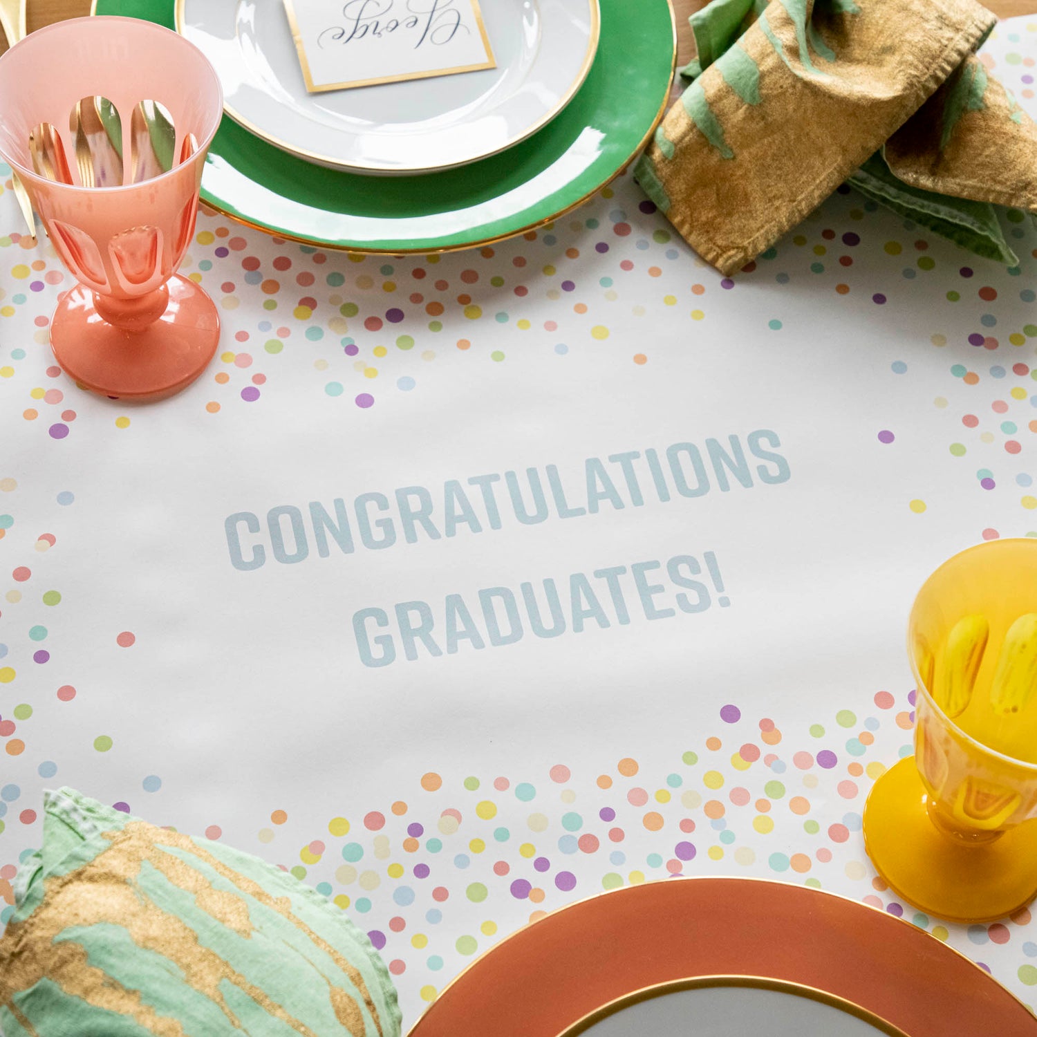 The Confetti Sprinkles Personalized Runner under a festive table setting, with &quot;CONGRATULATIONS GRADUATES!&quot; printed in light blue.