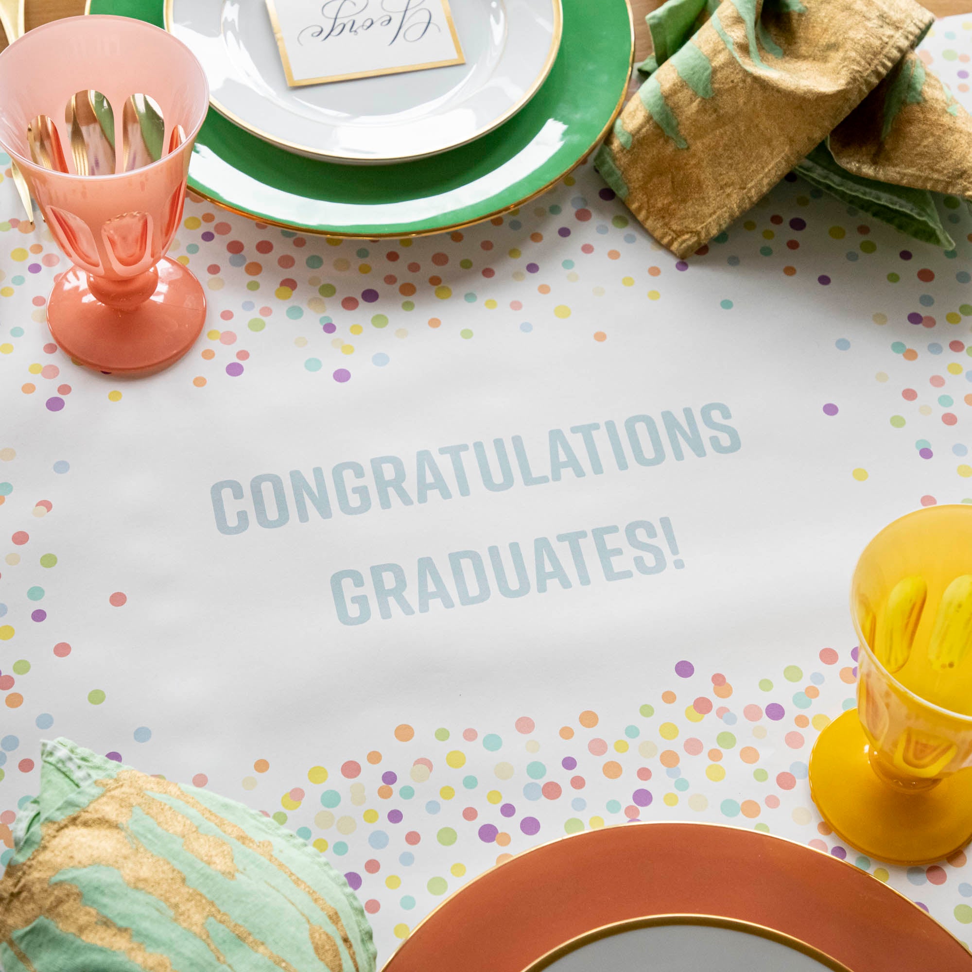 The Confetti Sprinkles Personalized Runner under a festive table setting, with &quot;CONGRATULATIONS GRADUATES!&quot; printed in light blue.