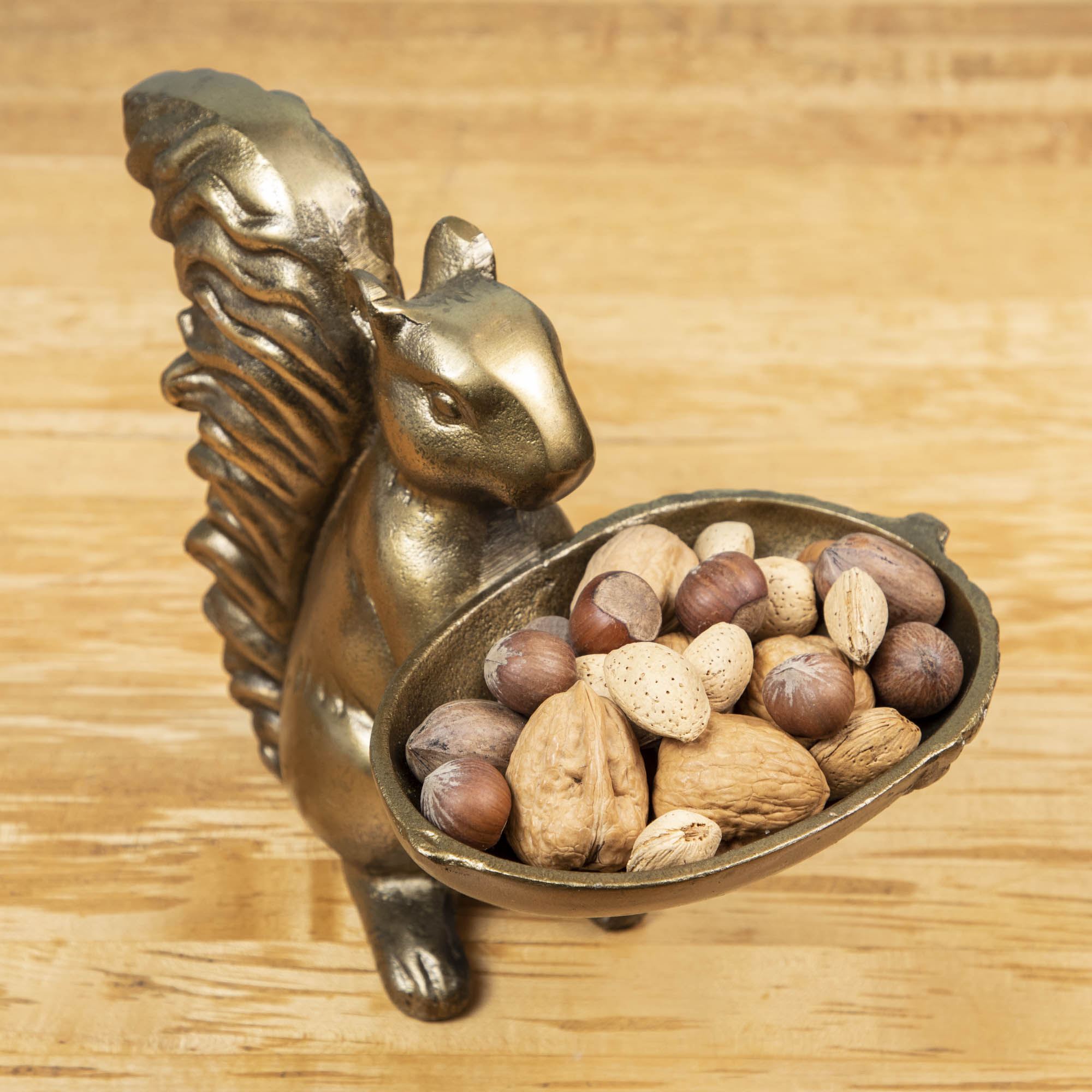 A bronze Accent Decor squirrel holding a bowl of nuts.