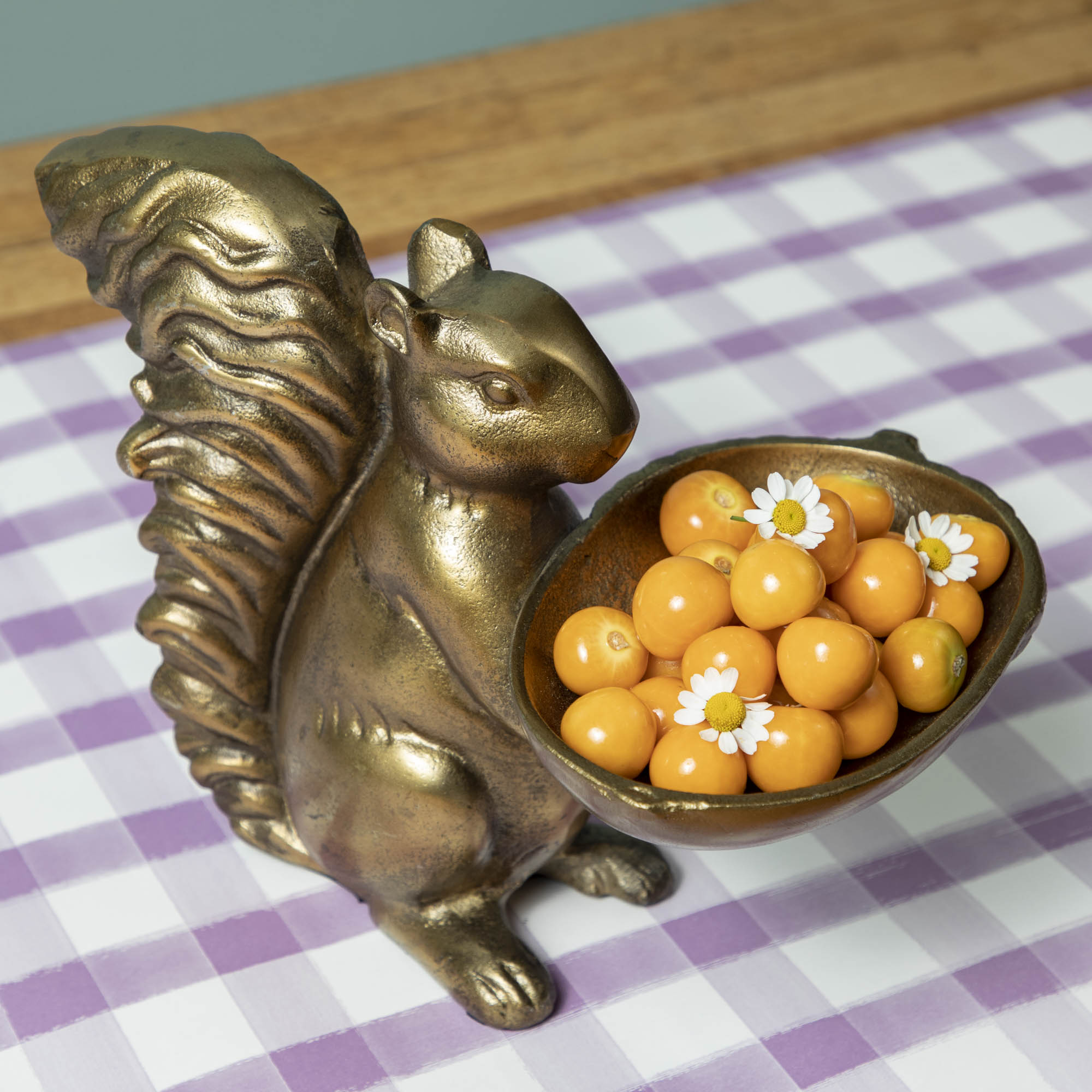 A bronze Accent Decor squirrel holding a bowl of tomatoes.