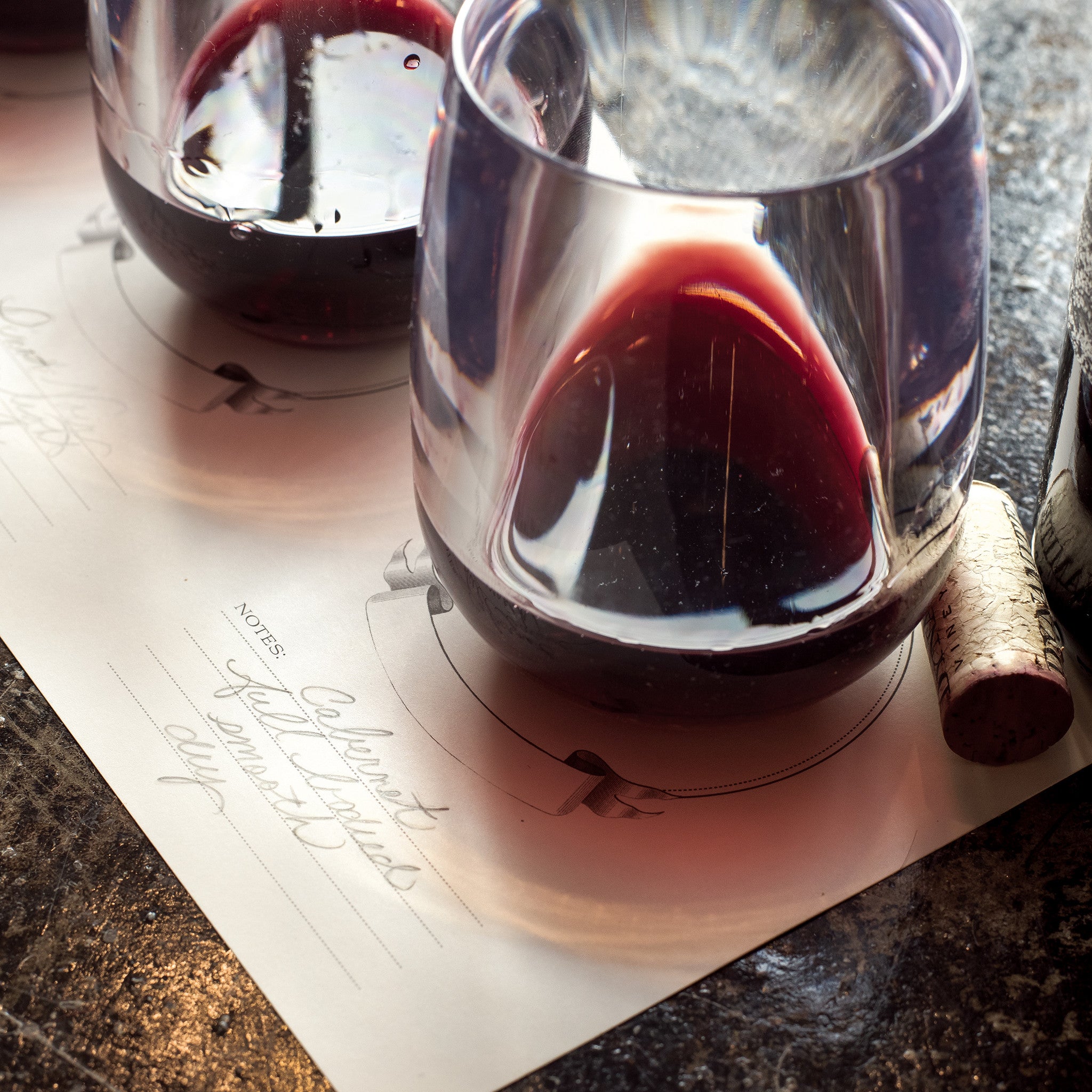 Close-up of a flight of red wines, set out and labeled on a Hester & Cook Tasting Paper.