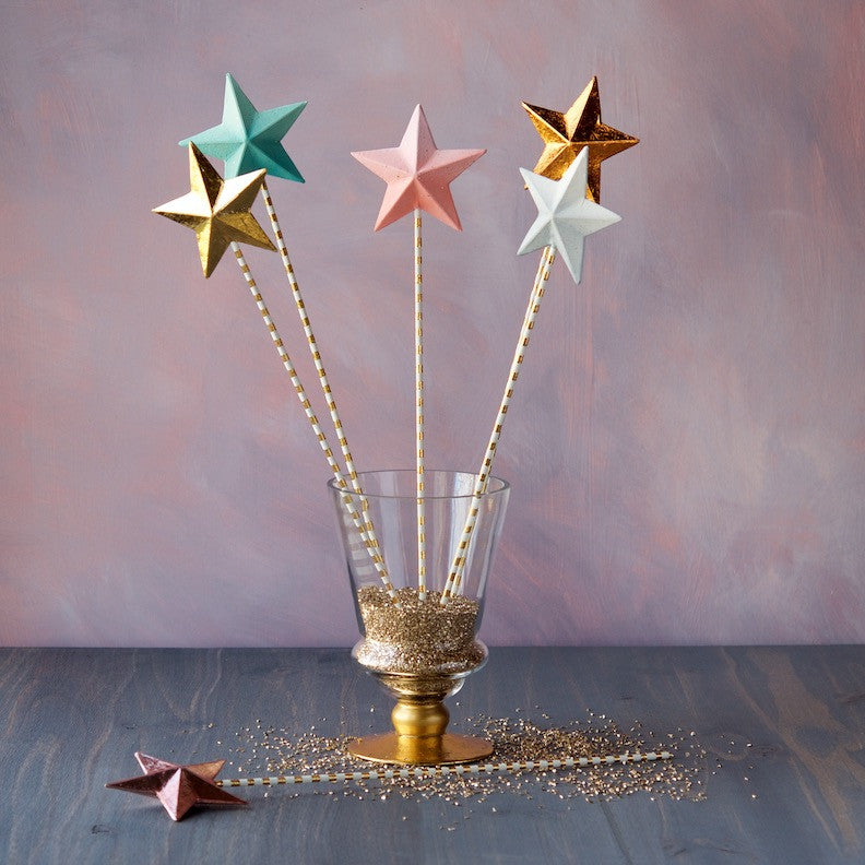 Five Glitterville Magic Wands on a striped background.