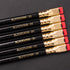 A stack of Blackwing Volume 20- Tribute to Tabletop Games pencils with gold lettering and distinctive square erasers on a black background.