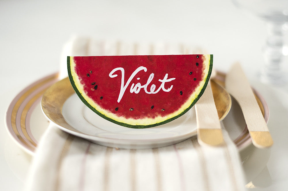 A die-cut, tented place card that resembles a round watermelon cross-section when flat, and a half-circle watermelon slice when folded and standing.