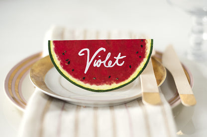 A die-cut, tented place card that resembles a round watermelon cross-section when flat, and a half-circle watermelon slice when folded and standing.