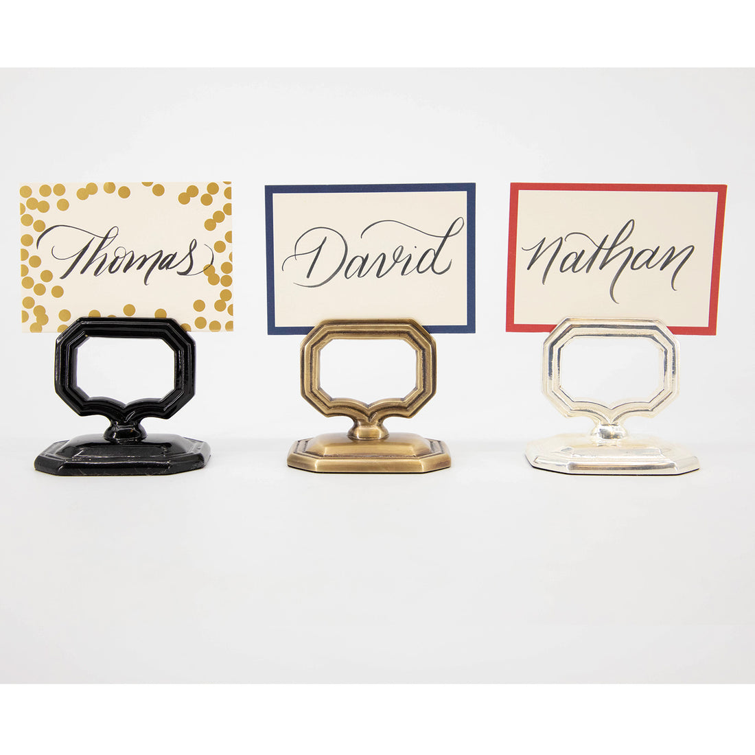 Three vintage-style Napkin Rings with Place Card Holders (Black, Brass and Silver) in a row, all three with different place cards.