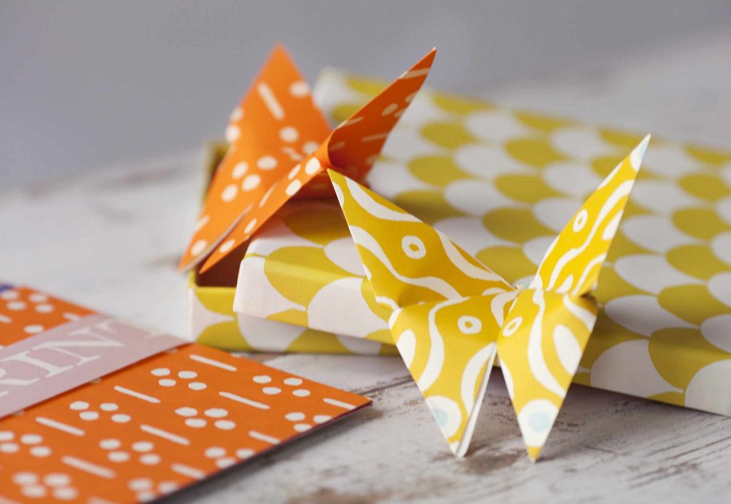Origami Cloud of Butterflies Kit with instructions and Cambridge Imprint patterned paper on a wooden table.
