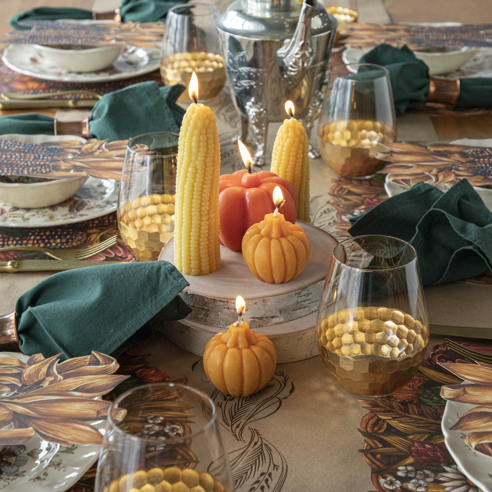 A collection of lit fall-themed candles on an elegant fall tablescape.