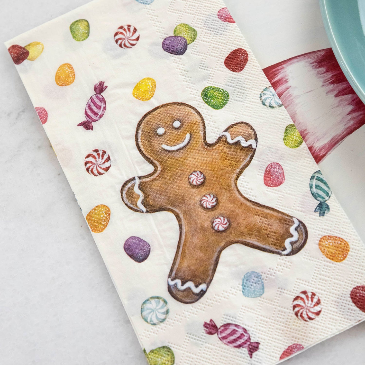 Close-up of a Gingerbread Guest Napkin next to a plate in a Christmas candy-themed place setting.