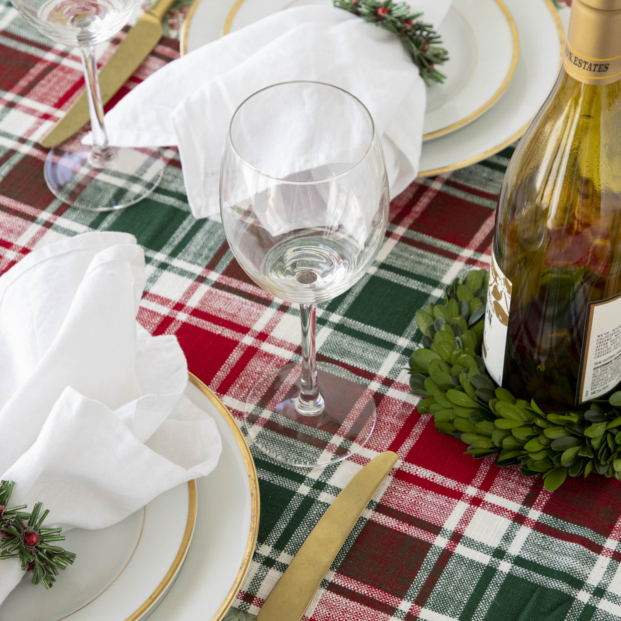 A Christmas table setting with beaded green and red napkin rings on white napkins.