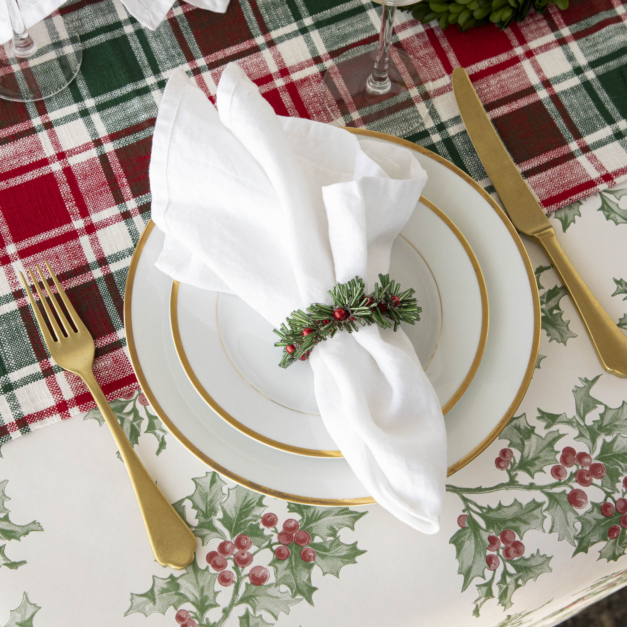 A Christmas table setting with beaded green and red napkin rings on white napkins.