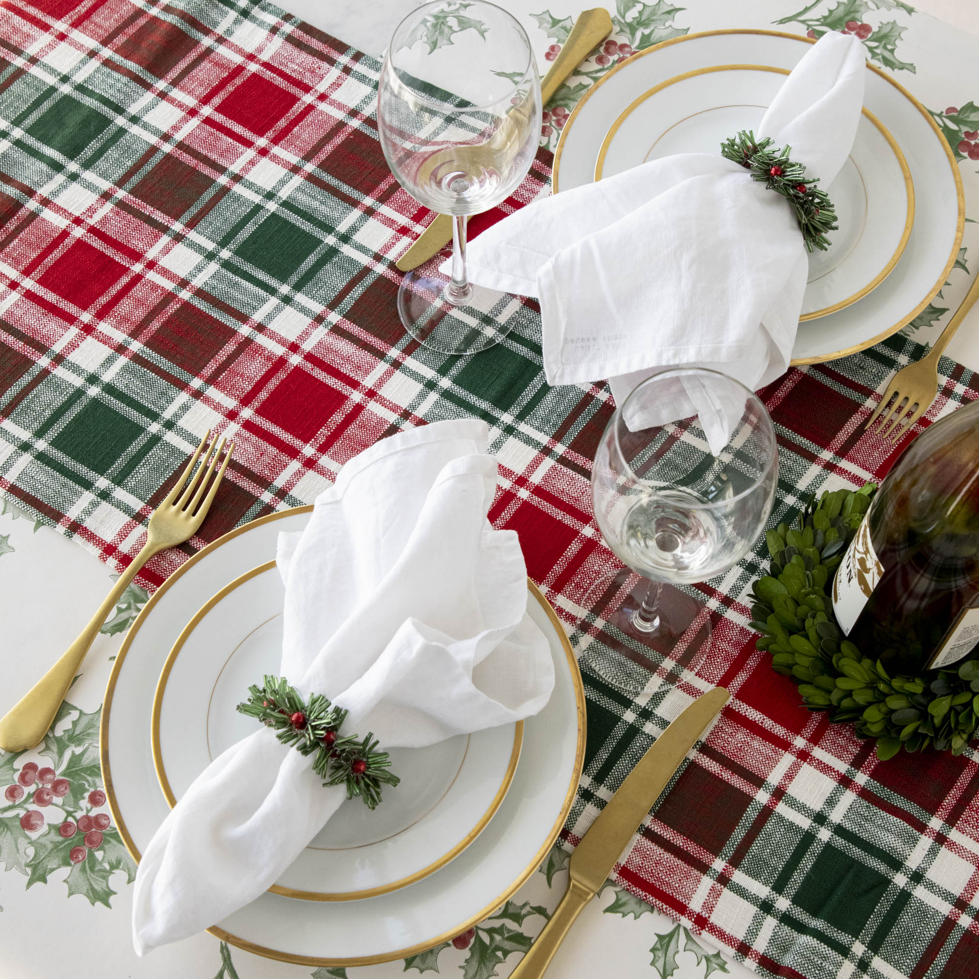 A Christmas table setting with beaded green and red napkin rings on white napkins.