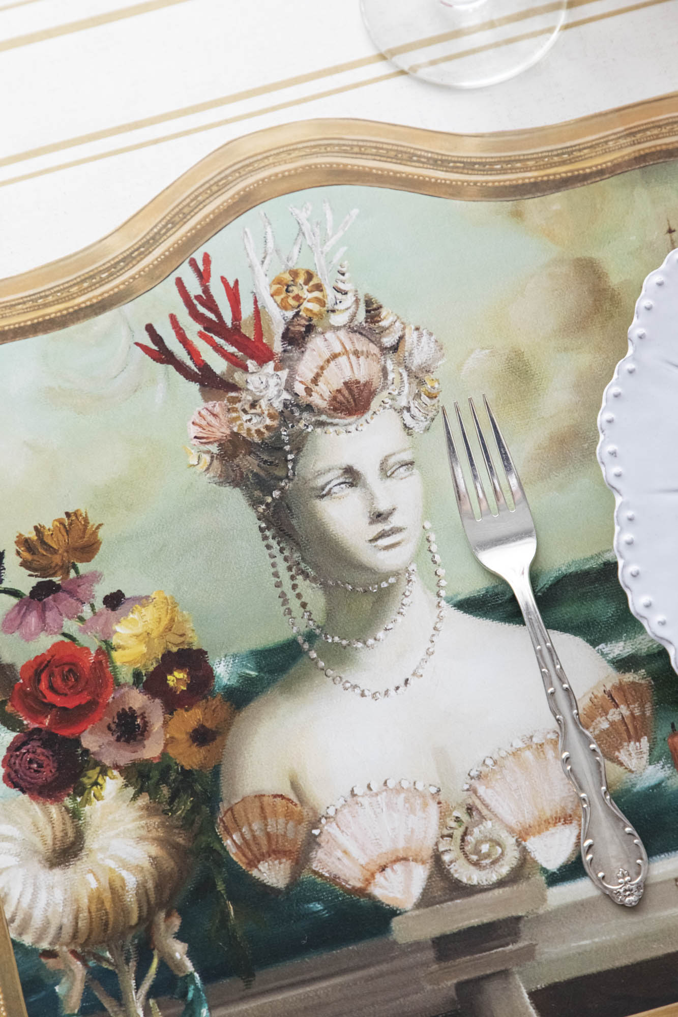 Close-up of the Die-cut Goddess of the Sea Placemat under an elegant place setting, showing the artwork in detail.
