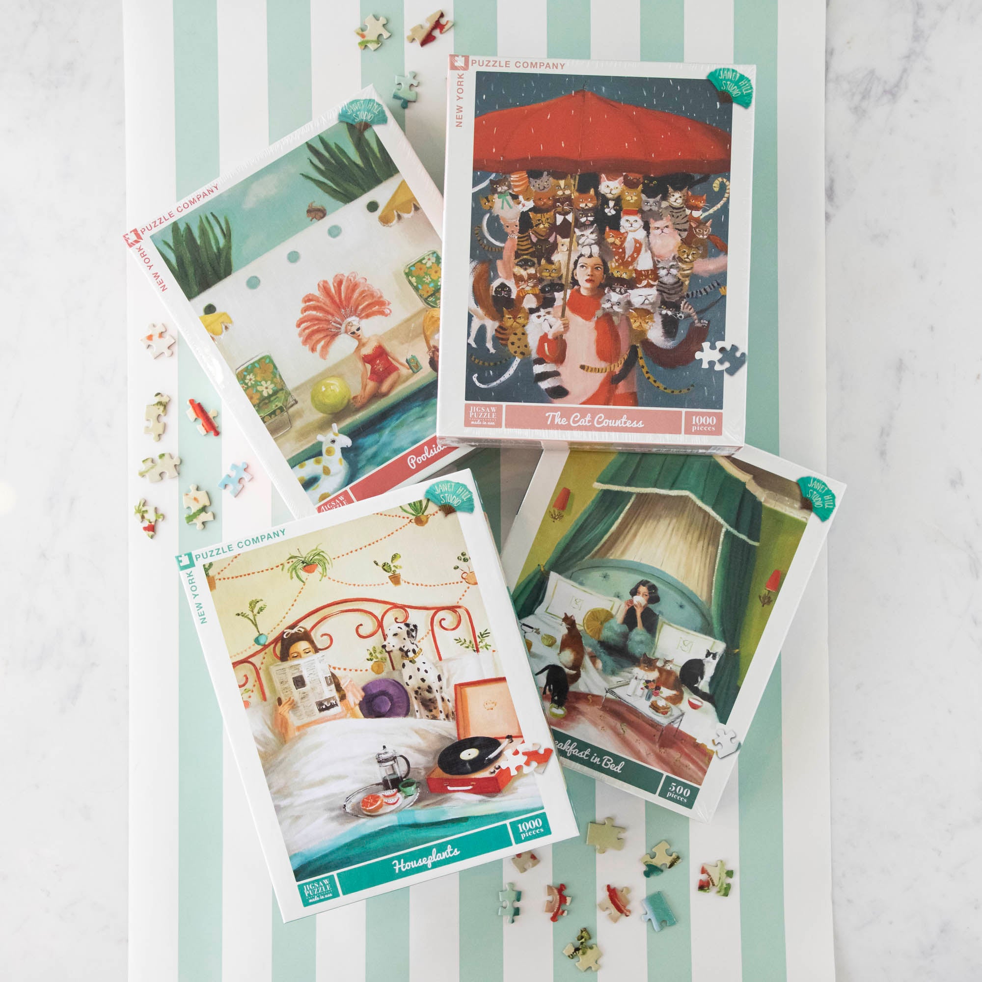 Four Janet Hill puzzles on a table.