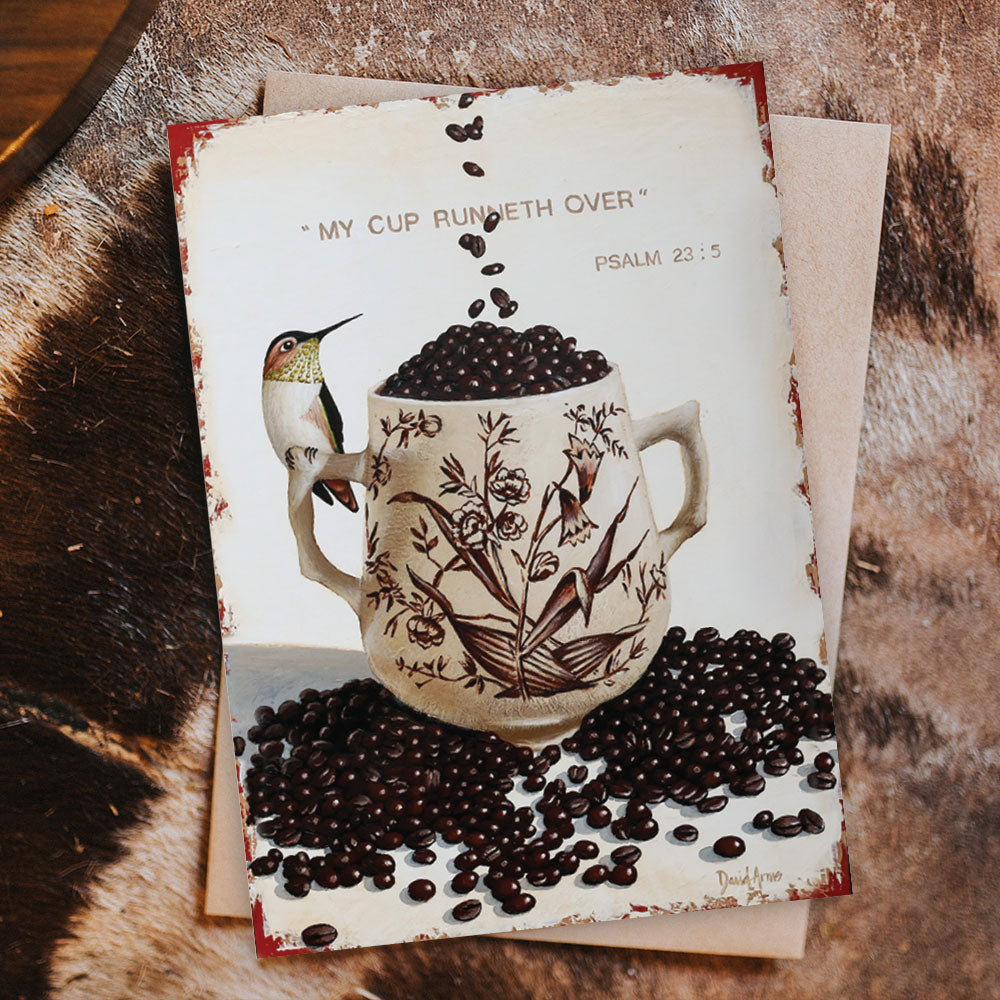 Sentence with product name and brand name: An illustration of the My Cup Runneth Over (Coffee Beans) Notecard surrounded by coffee beans with a hummingbird and the phrase &quot;my cup runneth over - psalm 23:5&quot; written on a handwritten note for that personal, by David Arms.