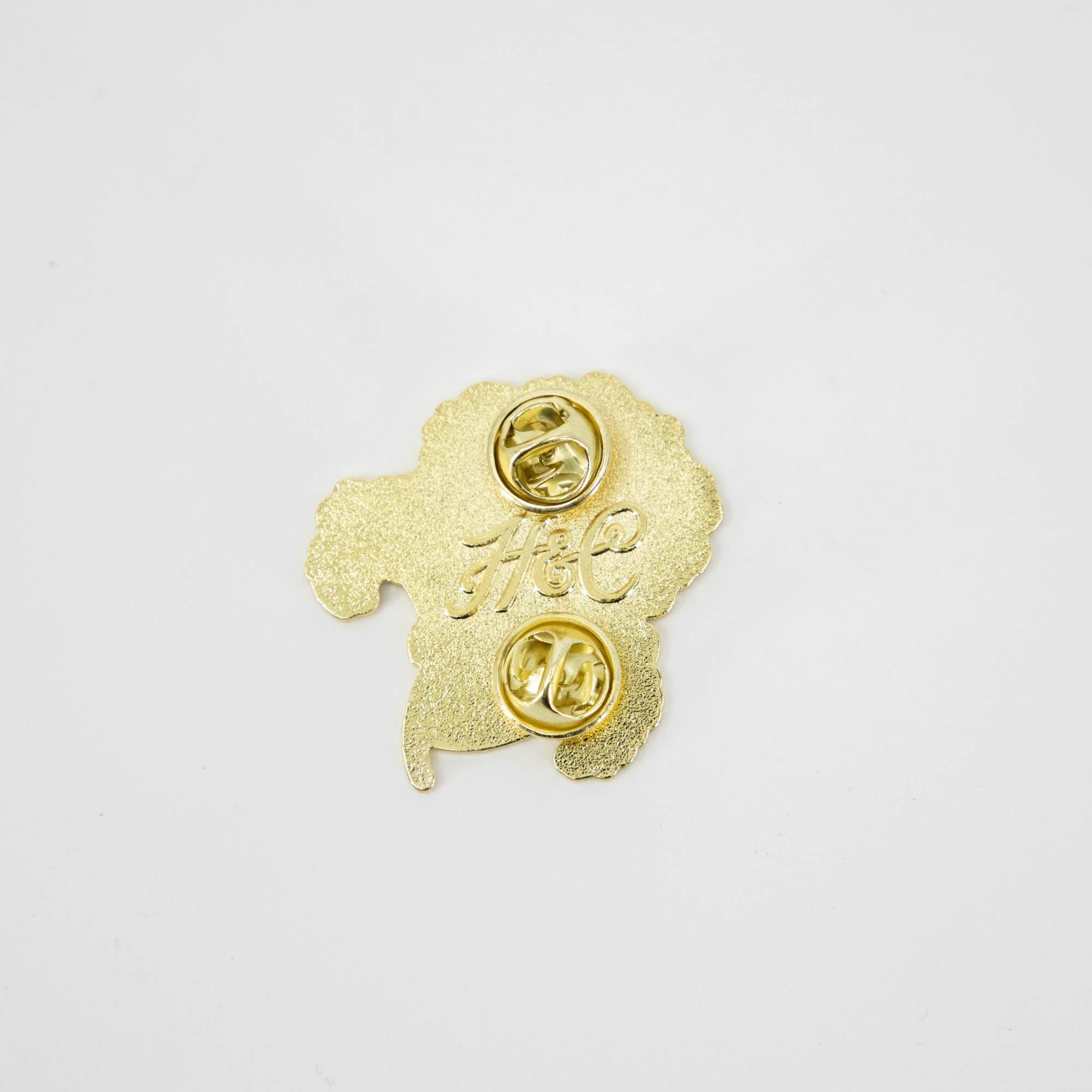 A Geranium Enamel Pin from Hester & Cook featuring a stylized gold poodle.
