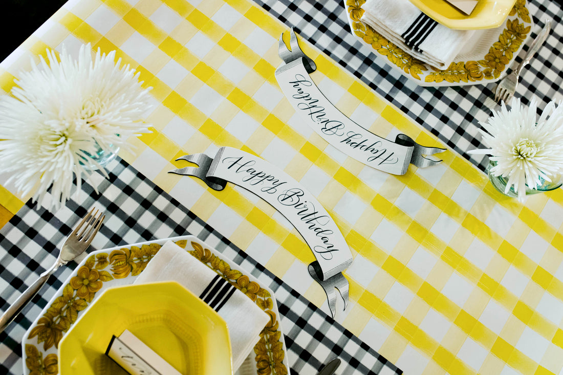 An elegant table setting in black, white and yellow featuring Classic Black Banner Table Accents with &quot;Happy Birthday&quot; written on them in beautiful script.