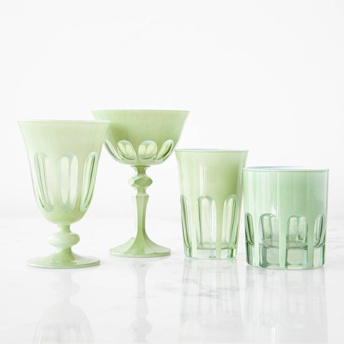 A set of SIR/MADAM Rialto Pale Sage Glasses and a bowl on a marble table.