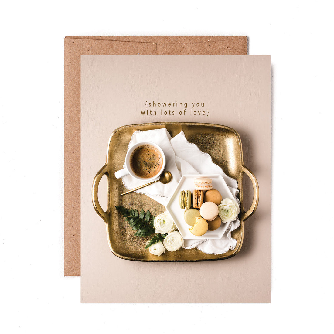 A top-down photo of a gold tray on a tan background, with a white cup of hot cocoa, a white plate of macaroons and white rose blooms, &quot;{showering you with lots of love}&quot; printed above the tray.