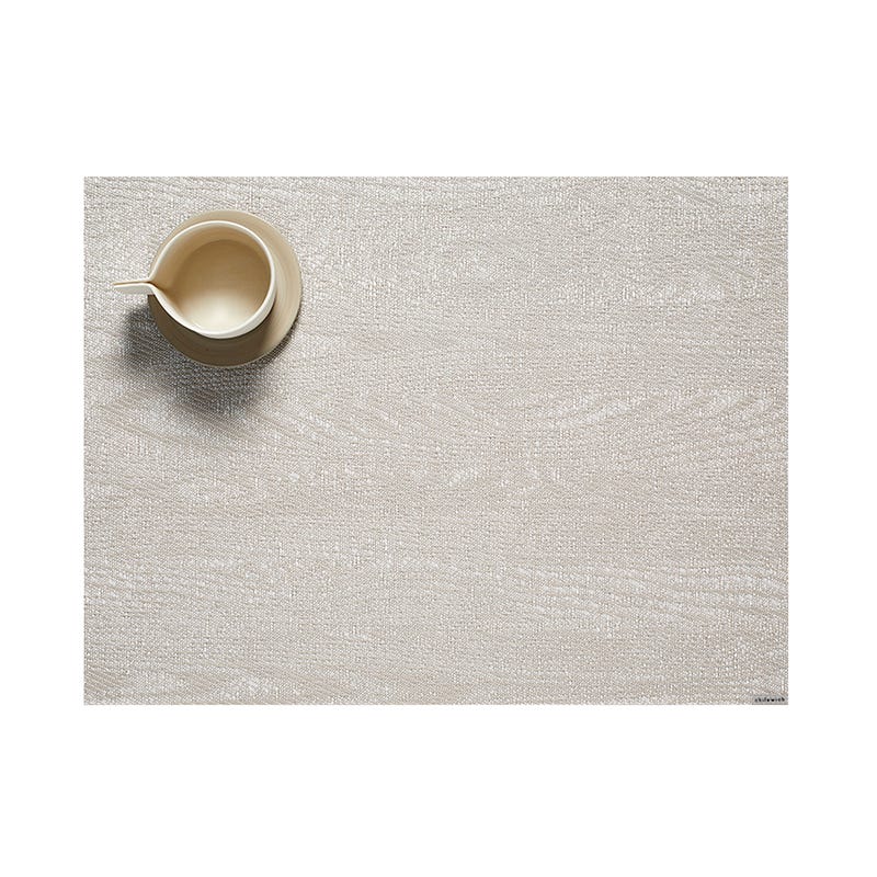 A ceramic jug placed on a textured Chilewich Woodgrain Table Mat with ample negative space, suitable for indoor-outdoor use.