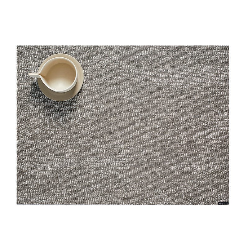 A ceramic jug placed on a textured Chilewich Woodgrain Table Mat with ample negative space, suitable for indoor-outdoor use.