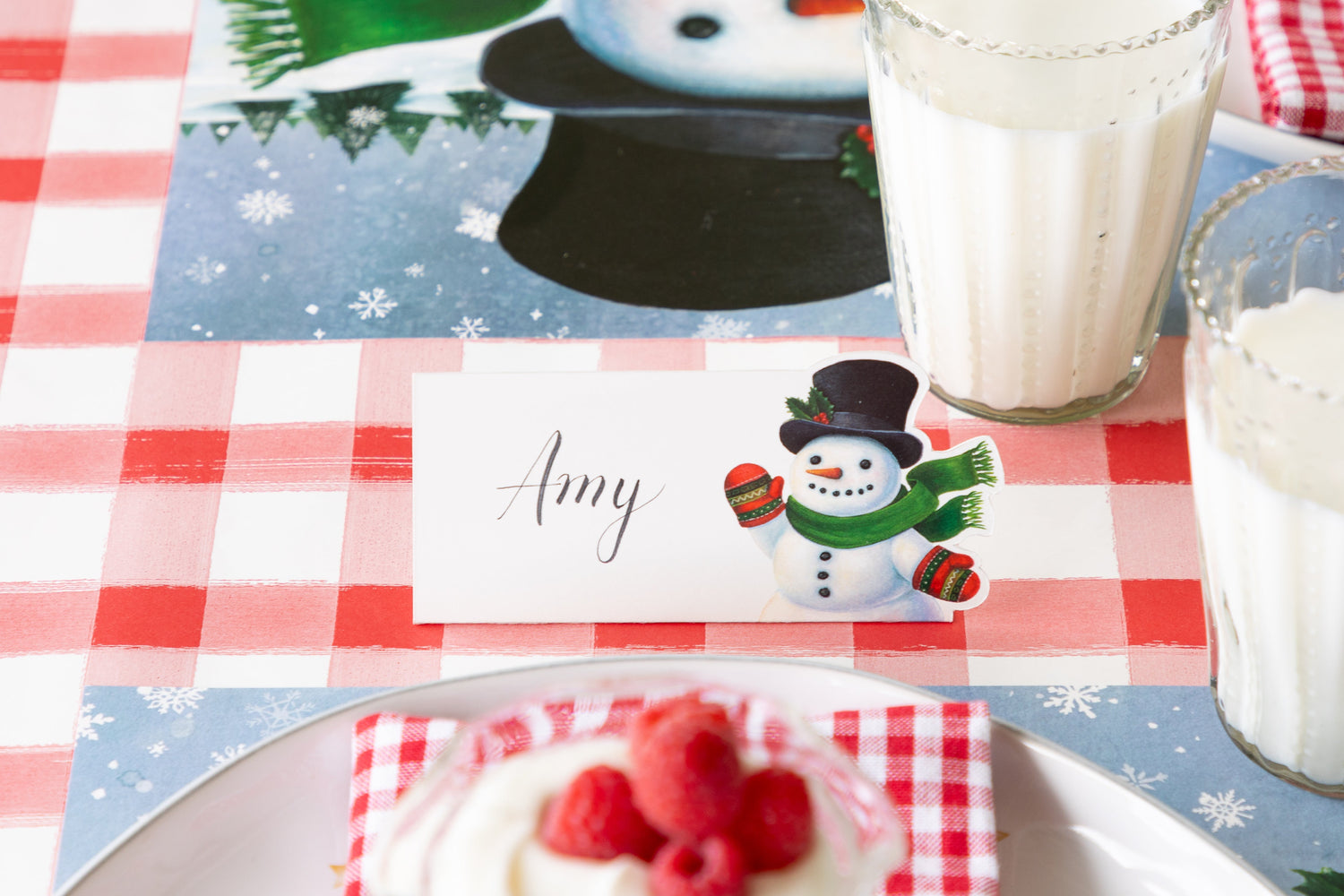 A Snowman Place Card with "Amy" written on it, behind a place setting.