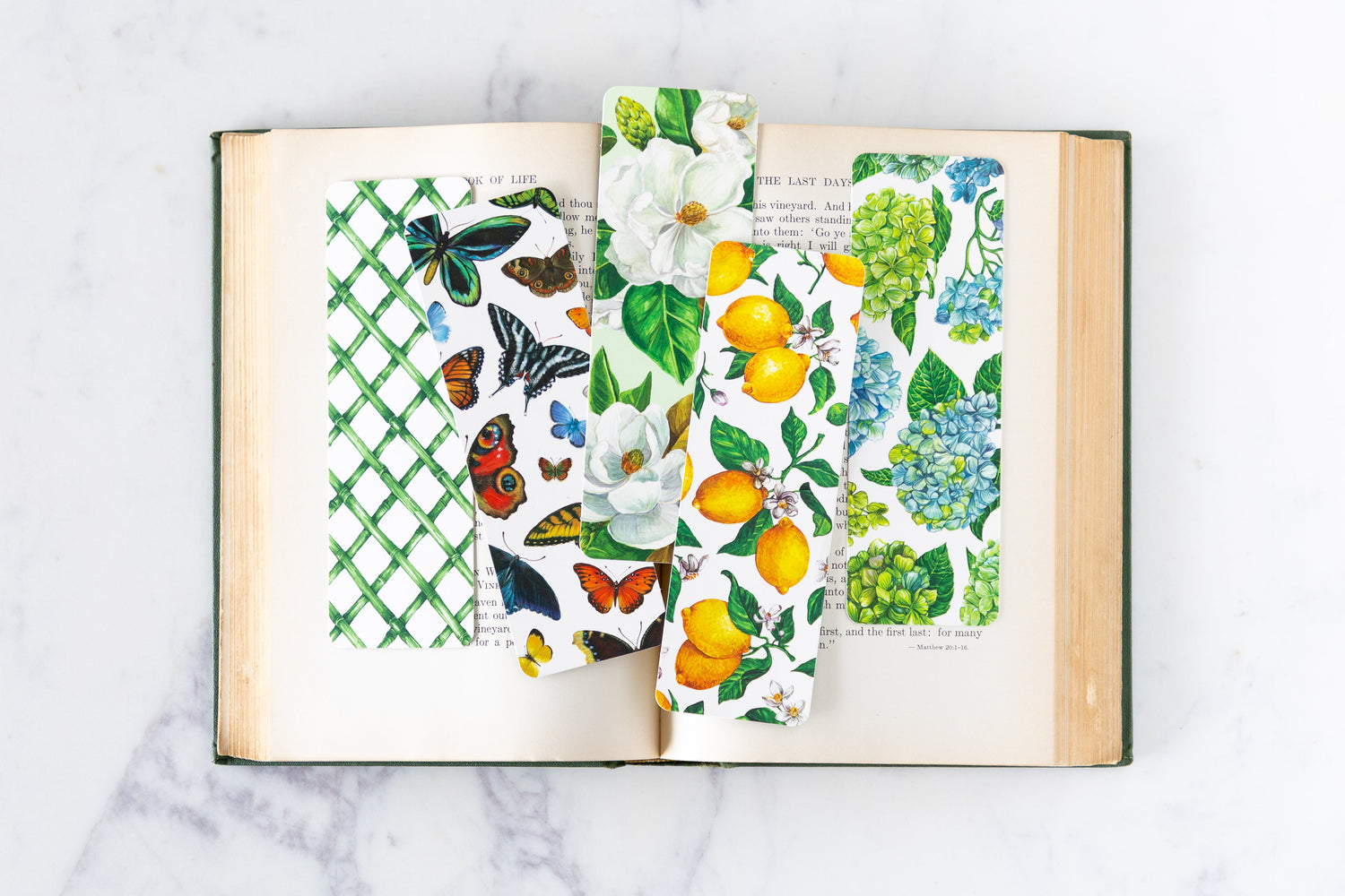 An open book on a marble table with various Hester &amp; Cook Bookmarks inside.