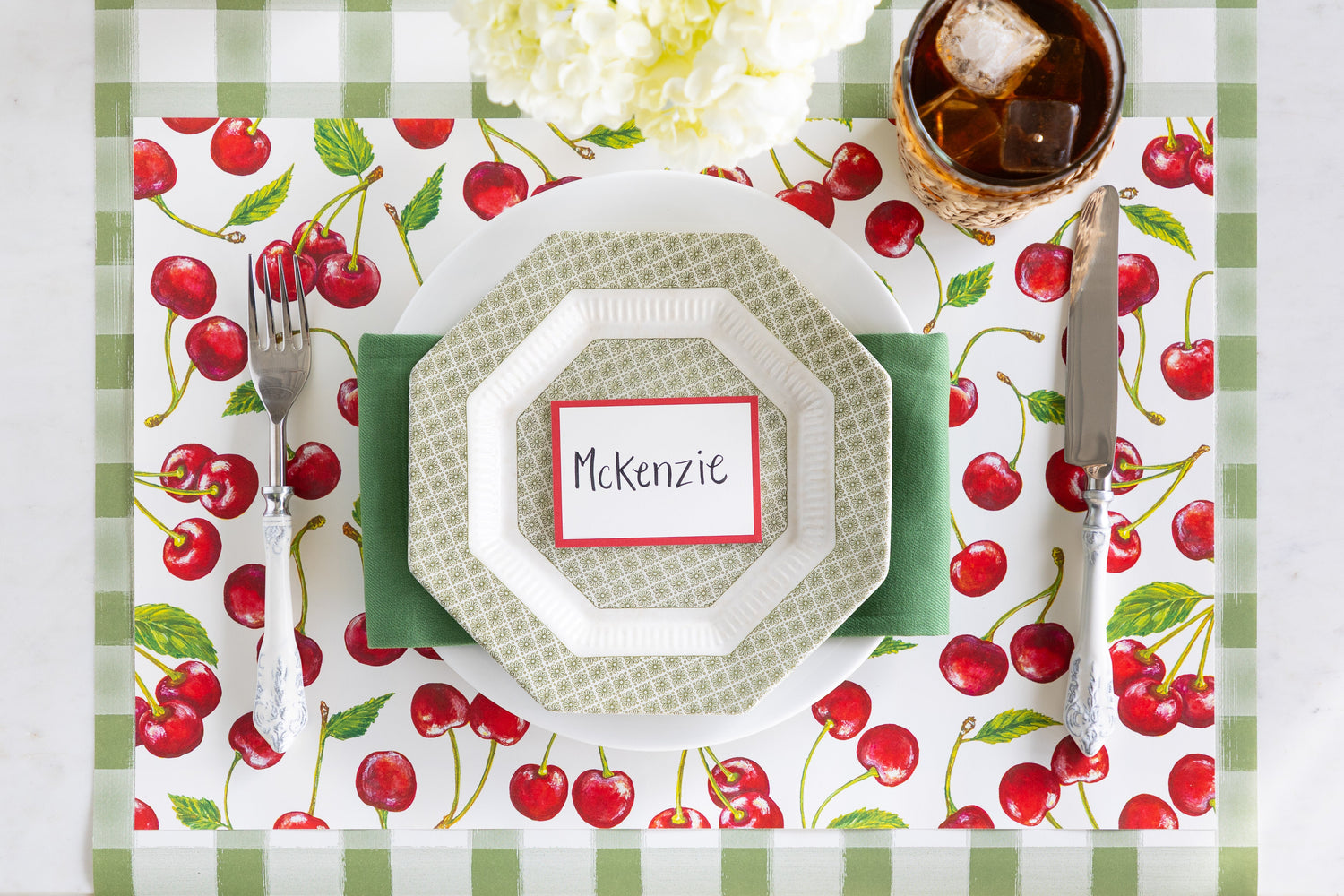 A summer place setting featuring the Cherries Placemat, Red Frame Place Card and vintage dinnerware on the Moss Painted Check Runner.