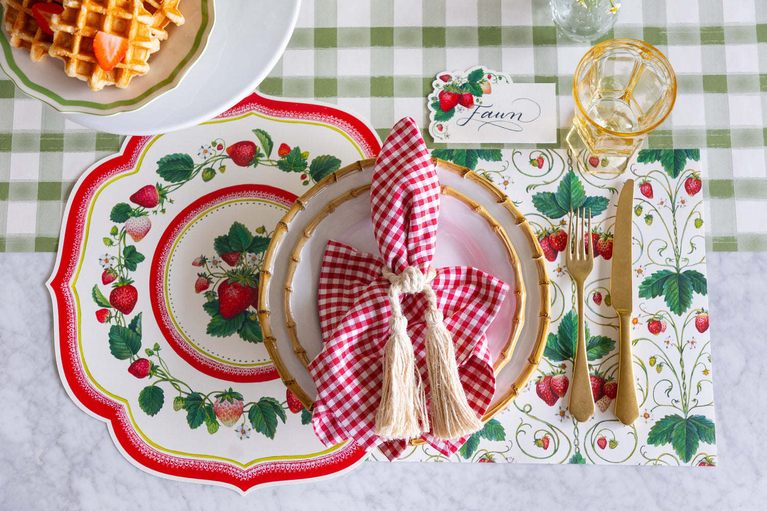 An elegant place setting featuring the Die-cut Strawberry China and Strawberry Fields Placemats, Strawberries Place Card, and bamboo dinnerware on the Moss Painted Check Runner.