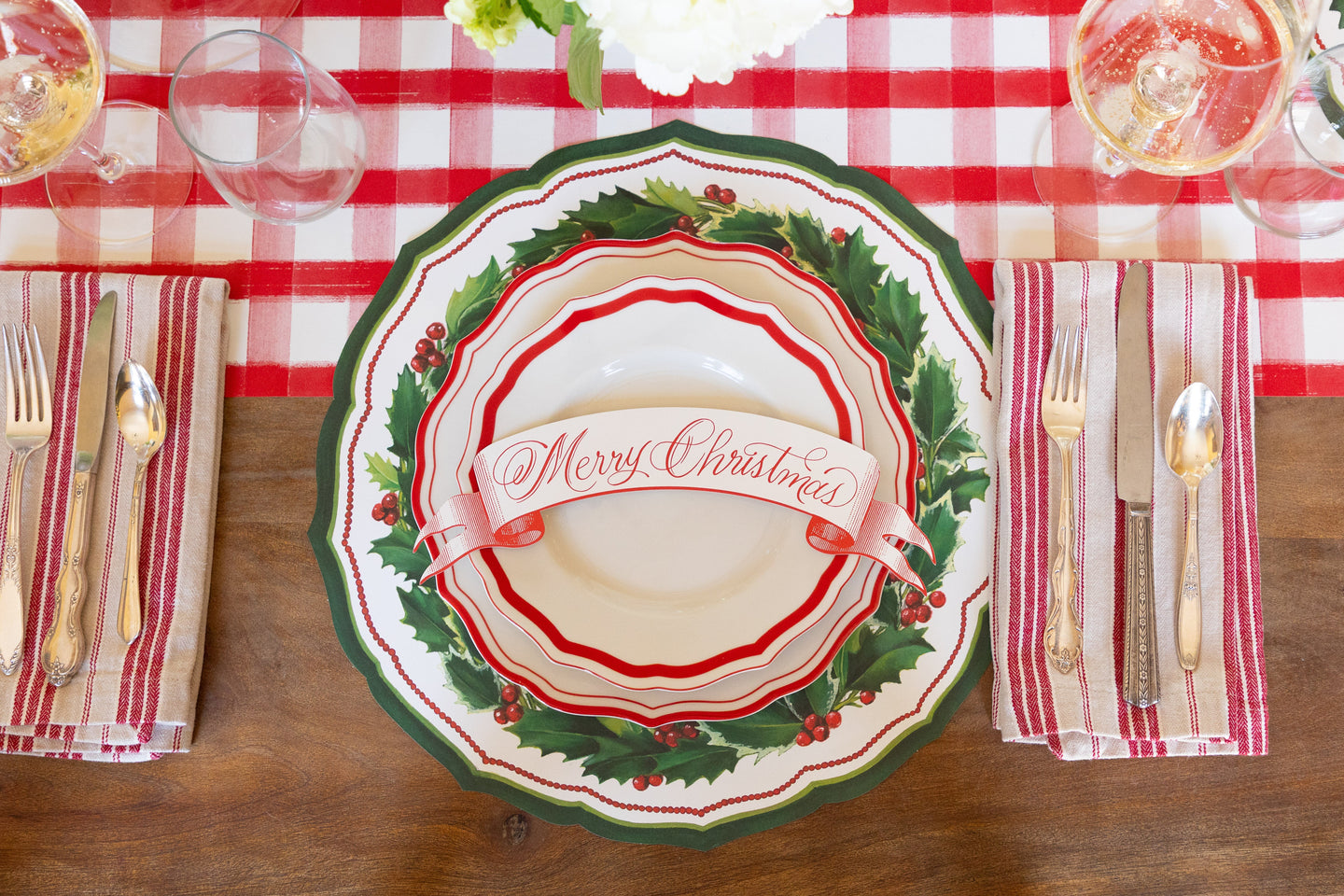 Holiday tablesetting with the Die-cut Holiday Holly China Placemat with red and white plates and a table accent. 