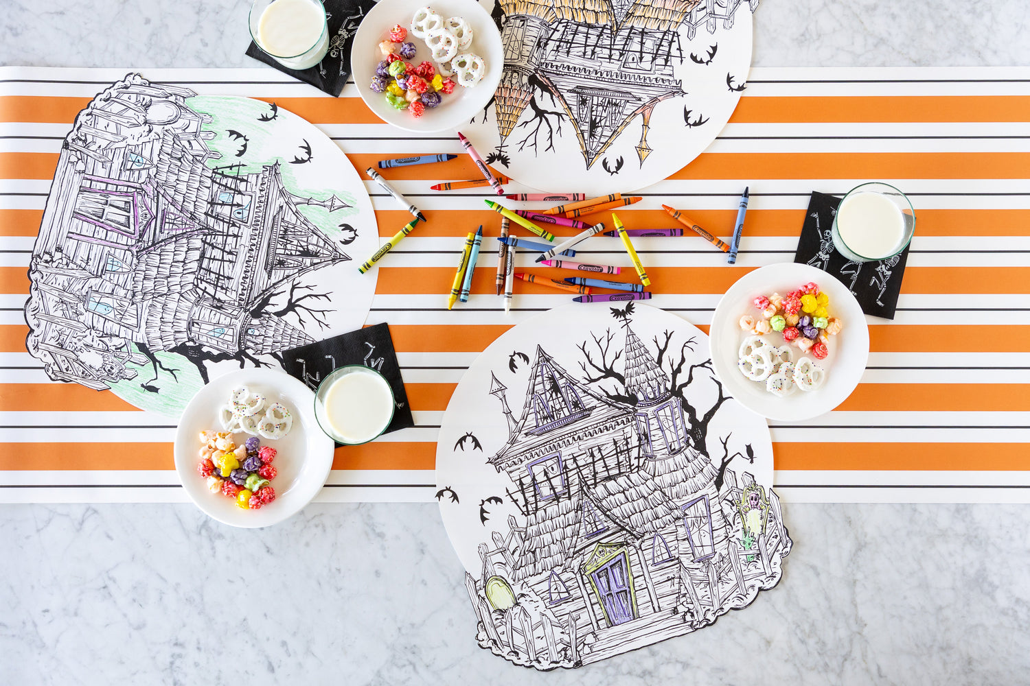 A table with three Die-cut Coloring Haunted House Placemats, crayons, bowls of treats and glasses of milk on the Orange &amp; Black Awning Stripe Runner.
