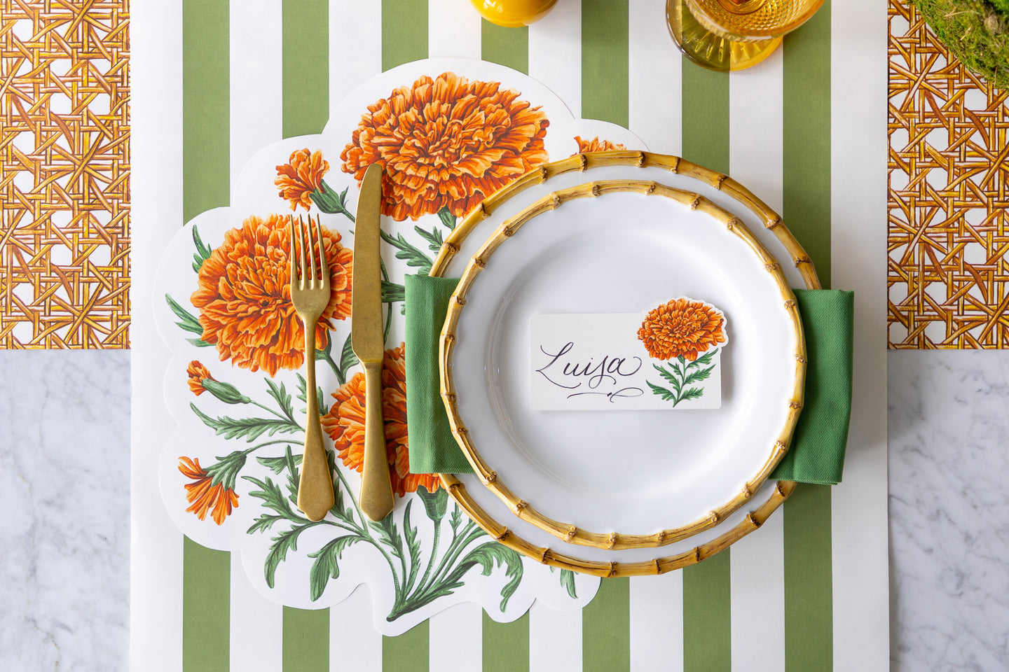 An elegant place setting featuring the Die-cut Marigold Bouquet Placemat, Marigold Bloom Place Card, Moss Classic Stripe Runner and Rattan Weave Runner.