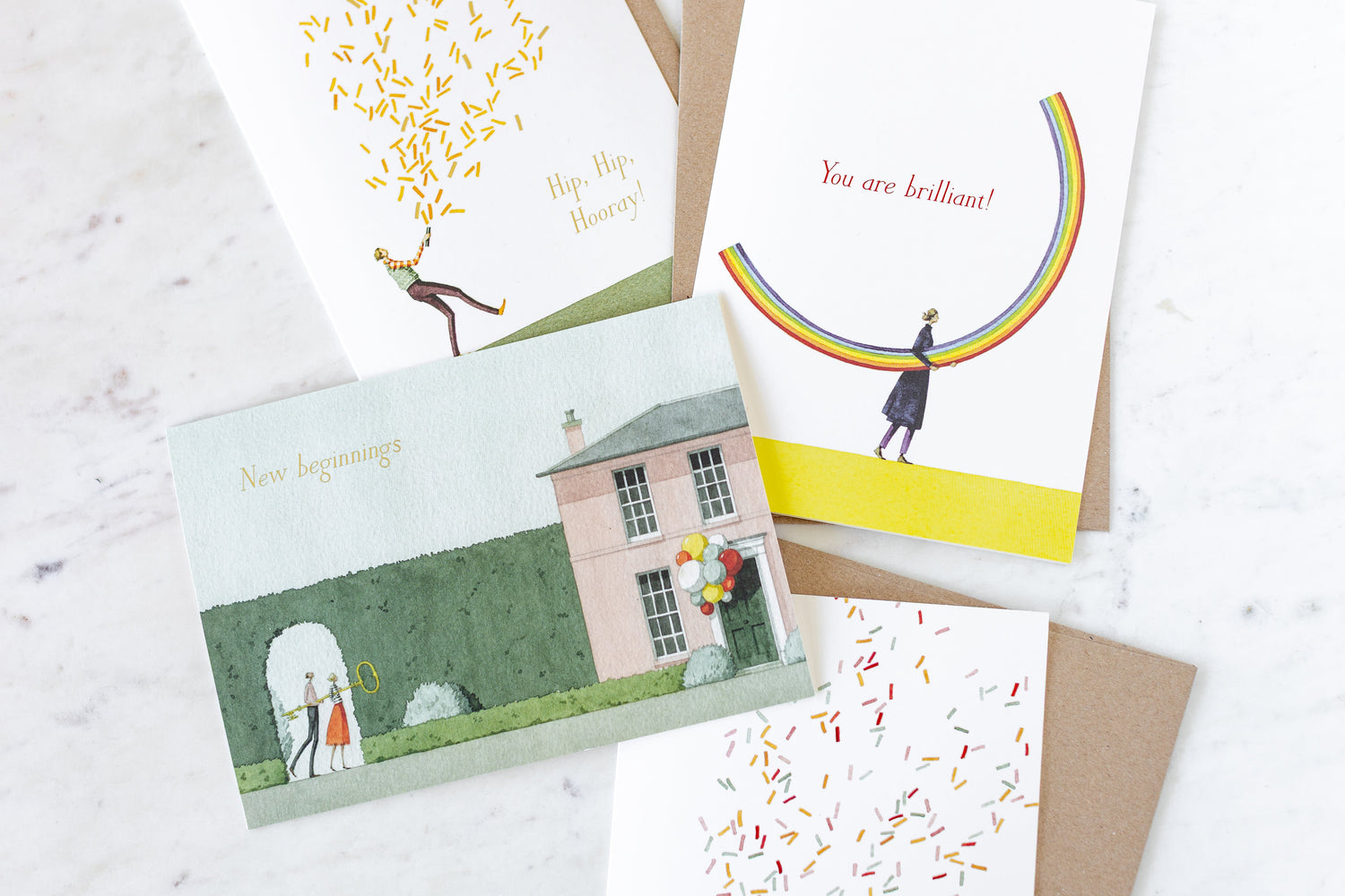 An assortment of Laura Stoddart greeting cards arranged on a table with kraft envelopes.