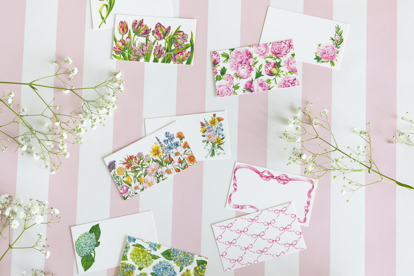 Group of Tiny Note cards on a pink and white striped table runner with baby's breath flowers scattered around. 