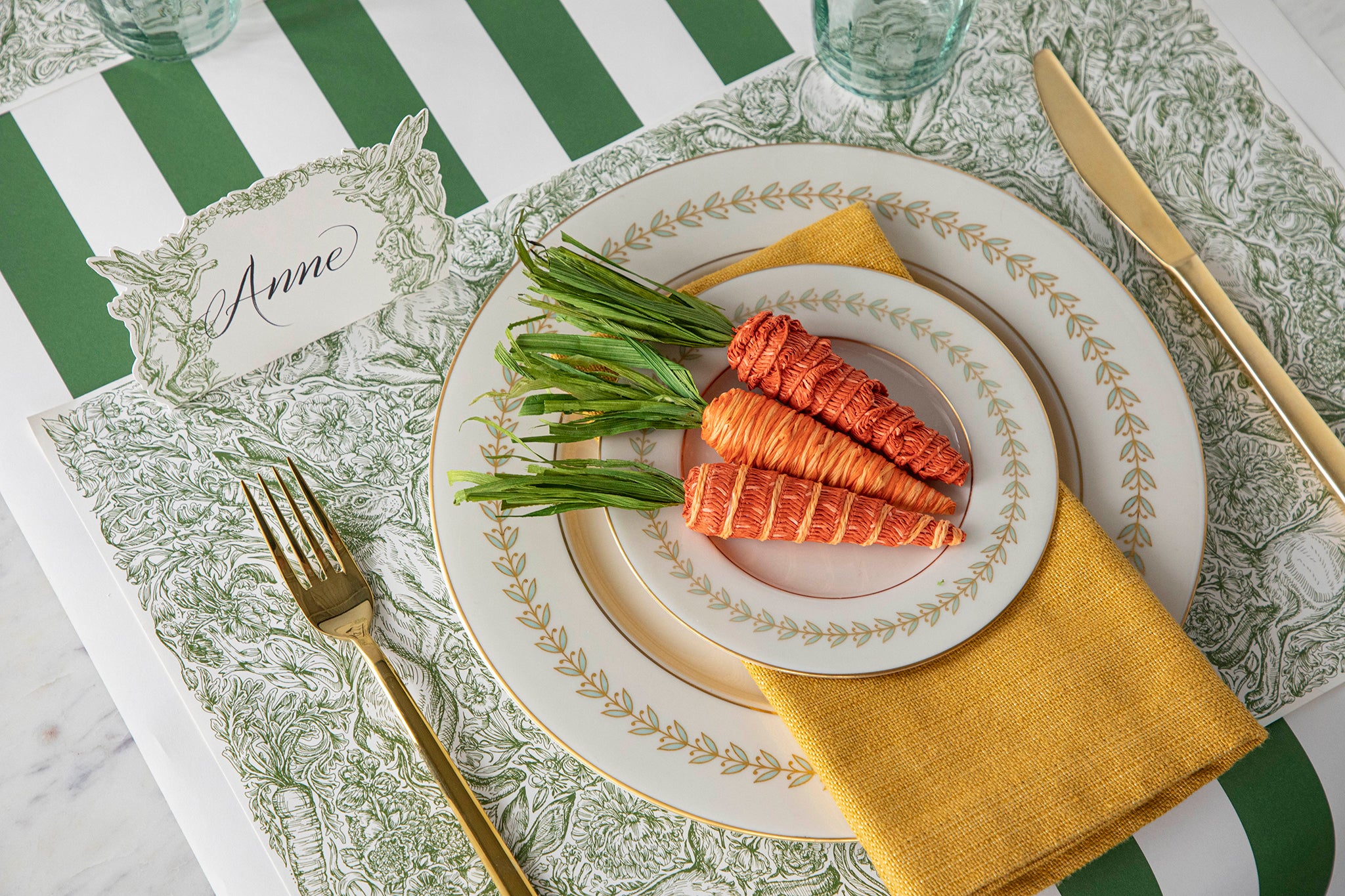 A place setting with carrots on a green and white plate.