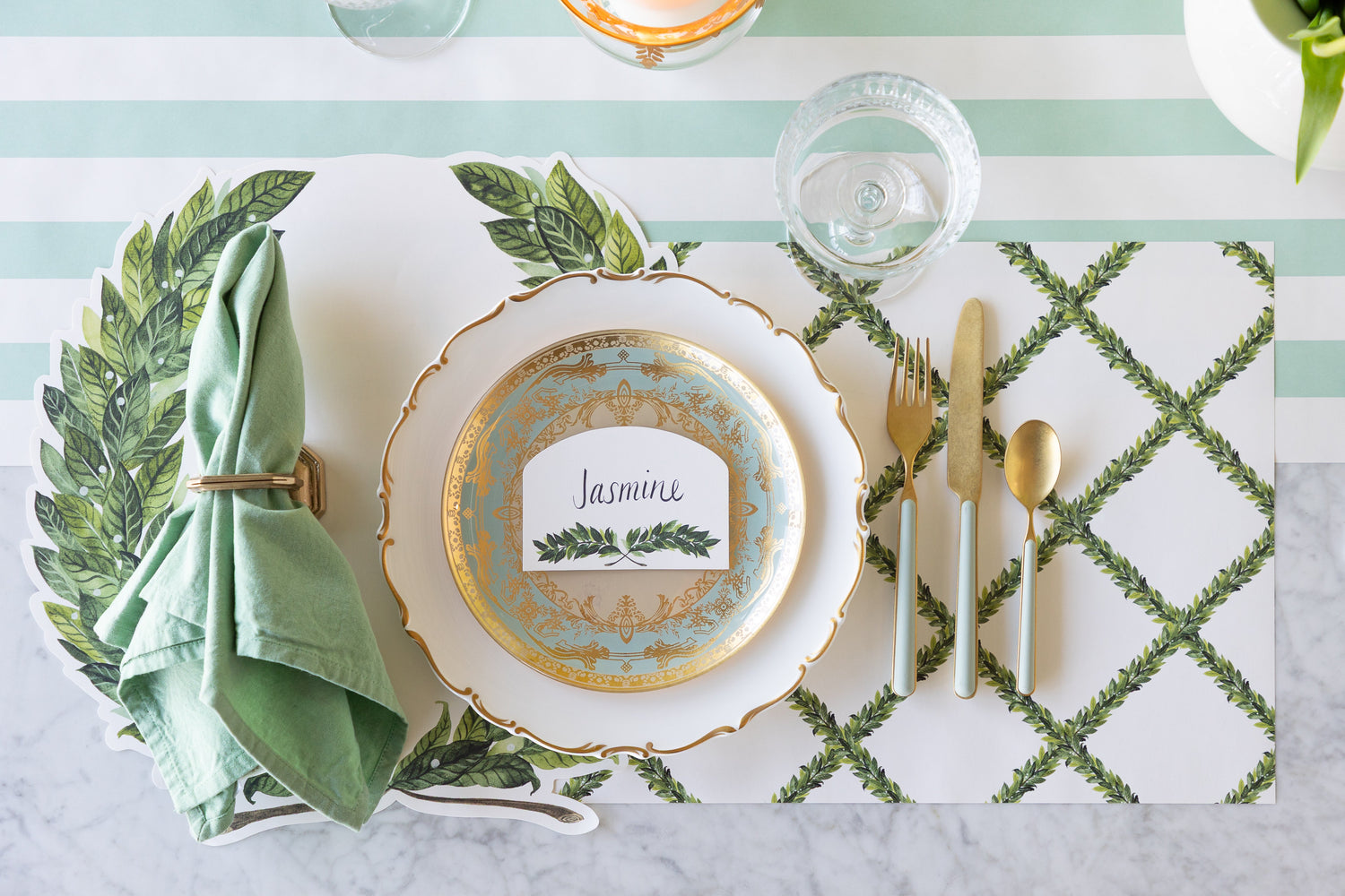 An elegant place setting featuring the Die-cut Laurel Wreath and Laurel Lattice Placemats, seafoam and gold dinnerware and Laurel Place Card on the Seafoam Classic Stripe Runner.