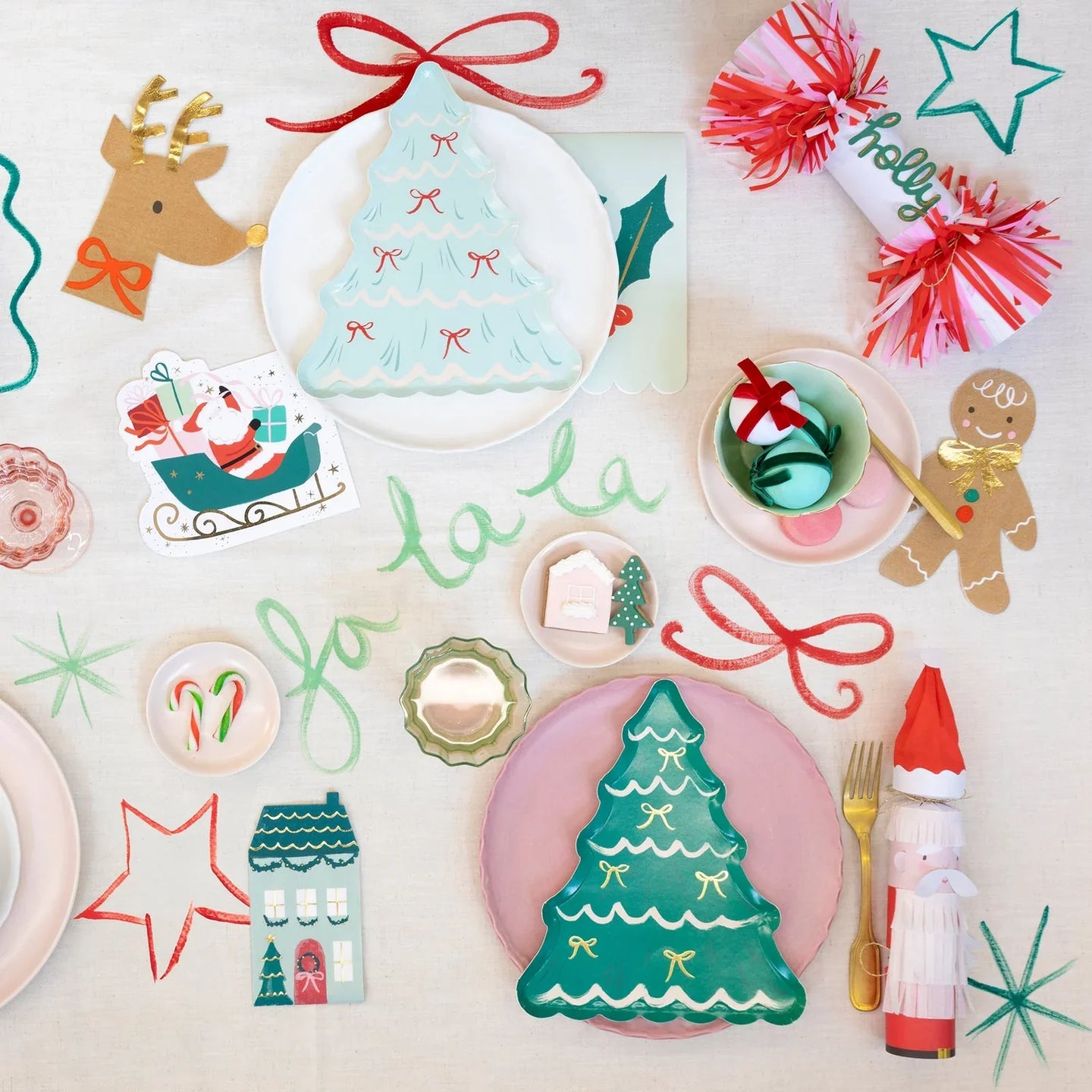 A festive Christmas table setting featuring Meri Meri tree shaped plates, festive crackers, Christmas napkins and colorful drawings.