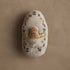 Decorative egg with embroidered designs of a chick and rabbit on a beige background.