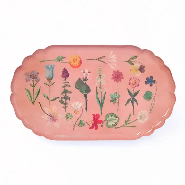 An oval pink enamel serving tray with scalloped edges, featuring illustrated flowers, on a white background. 