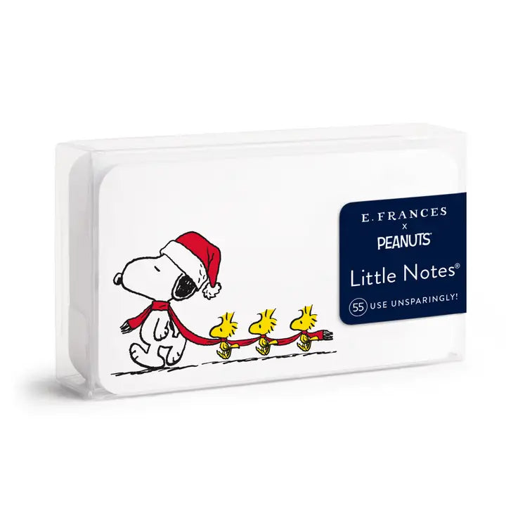 E. Frances x Peanuts Little Notes pad in a clear plastic sleeve, featuring a holiday-themed cover illustration of Snoopy and Woodstock with a dark blue brand label.