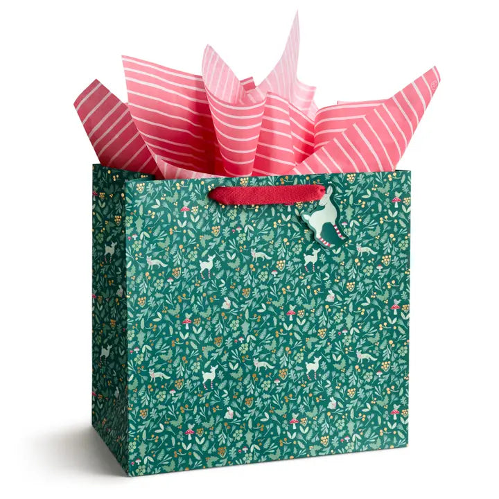 Gift bag with a pattern of animals and flowers, containing pink striped tissue paper.