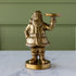 Gold Saint Nick Figurine holding a candle holder on a marble surface with a green wall background.