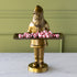 Gold statue of a Saint Nick holding a tray of peppermint candies against a green wall.
