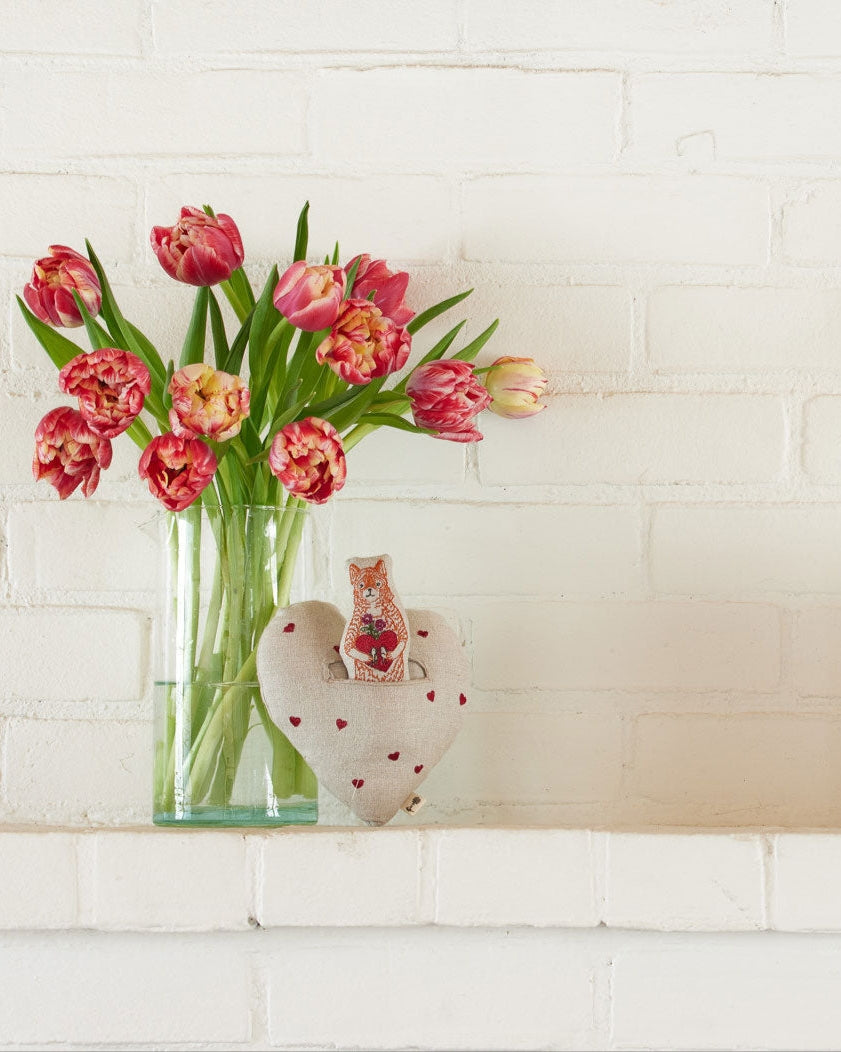 Vase with pink tulips on a white brick wall background.