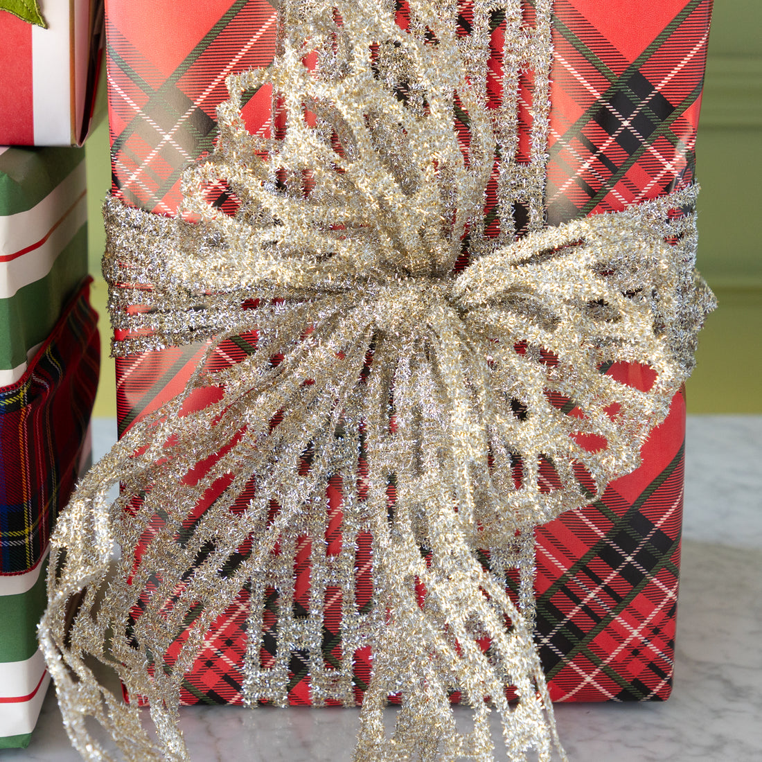 Gift wrapped in red plaid paper with a large silver bow in front