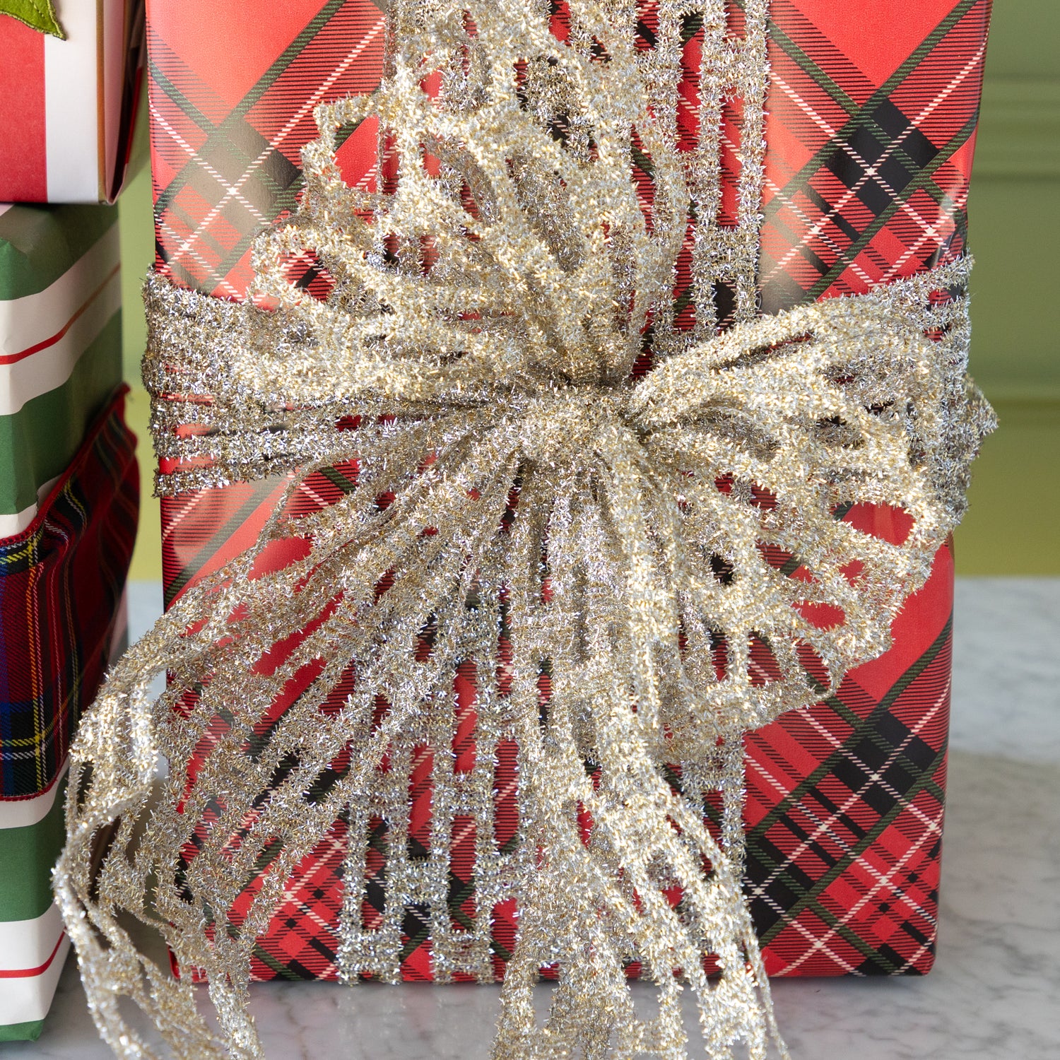 Gift wrapped in red plaid paper with a large silver bow in front